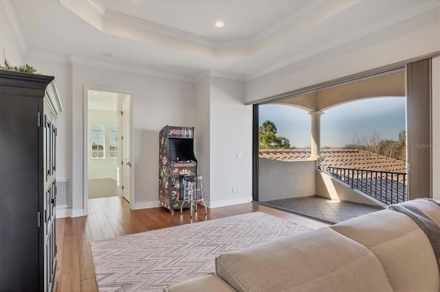 living room featuring baseboards, ornamental molding, wood finished floors, a tray ceiling, and recessed lighting