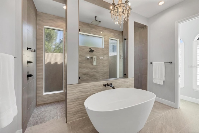 full bathroom with an inviting chandelier, a freestanding tub, walk in shower, baseboards, and tile patterned floors