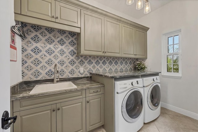 clothes washing area featuring washer and clothes dryer, cabinet space, light tile patterned flooring, a sink, and baseboards