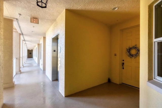 hall featuring elevator and a textured ceiling