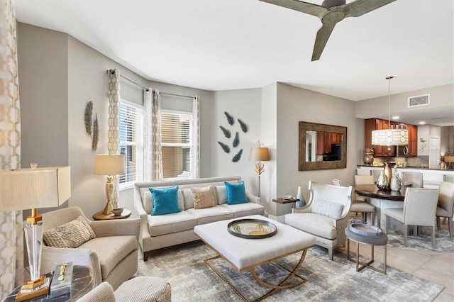 living area with light tile patterned floors, visible vents, and ceiling fan