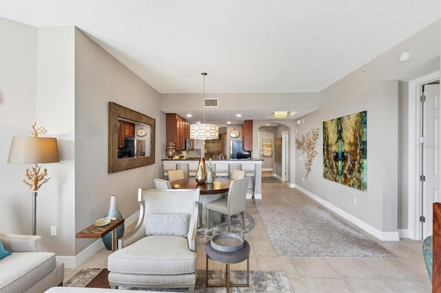 living room featuring light tile patterned floors, visible vents, arched walkways, and baseboards