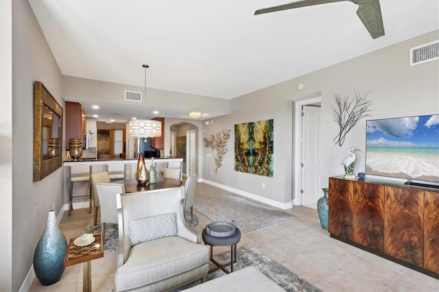 living room featuring light tile patterned floors, arched walkways, visible vents, and baseboards