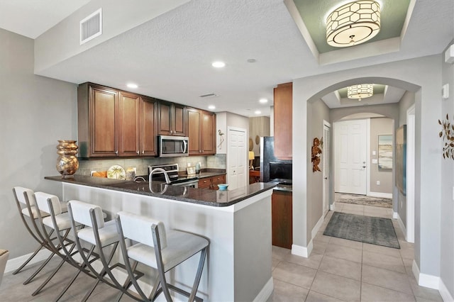 kitchen featuring tasteful backsplash, visible vents, a breakfast bar area, appliances with stainless steel finishes, and a peninsula