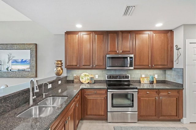 kitchen with tasteful backsplash, visible vents, dark stone counters, stainless steel appliances, and a sink