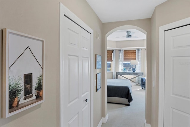 hall featuring arched walkways and carpet flooring