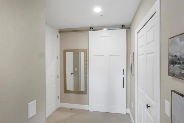 hallway featuring a barn door and baseboards