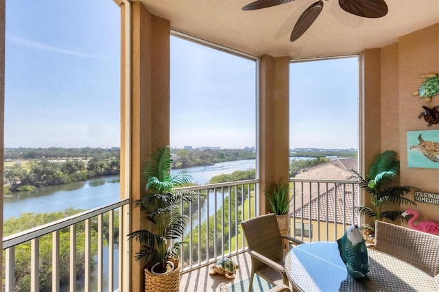 sunroom featuring a ceiling fan and a water view