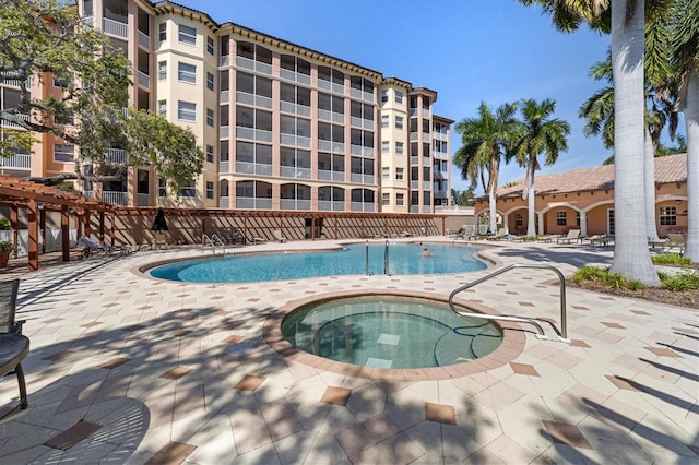 pool with a patio, a community hot tub, and fence