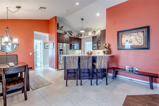 kitchen with lofted ceiling, a breakfast bar, hanging light fixtures, appliances with stainless steel finishes, and kitchen peninsula