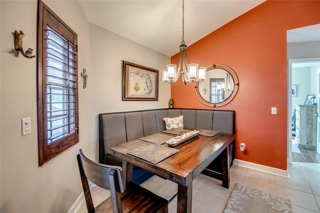 dining room with a notable chandelier, vaulted ceiling, and light tile patterned flooring