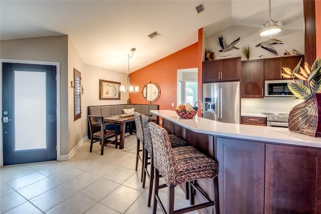 kitchen featuring pendant lighting, lofted ceiling, a kitchen bar, kitchen peninsula, and stainless steel appliances