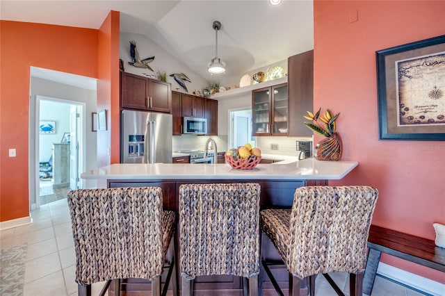 kitchen with vaulted ceiling, decorative light fixtures, backsplash, kitchen peninsula, and stainless steel appliances