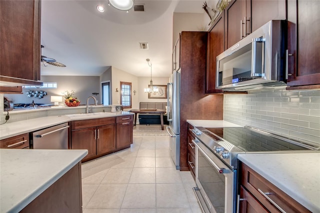 kitchen featuring light tile patterned flooring, appliances with stainless steel finishes, pendant lighting, sink, and decorative backsplash