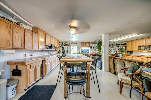 kitchen featuring backsplash, a breakfast bar area, ceiling fan, and light brown cabinets