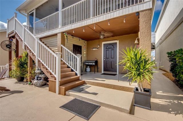 view of exterior entry featuring ceiling fan and a patio