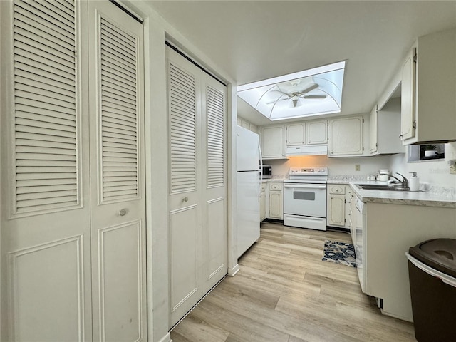 kitchen with sink, white cabinets, white appliances, and light hardwood / wood-style flooring