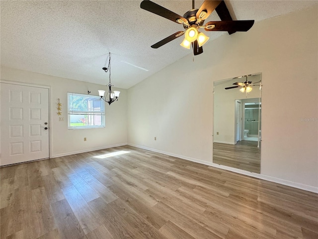 interior space with lofted ceiling, a notable chandelier, a textured ceiling, and light hardwood / wood-style flooring