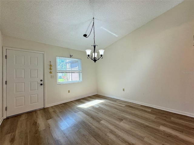 foyer entrance with wood-type flooring, a notable chandelier, and a textured ceiling