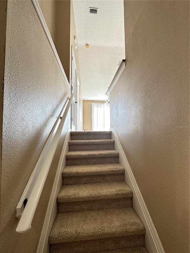 staircase with a textured ceiling