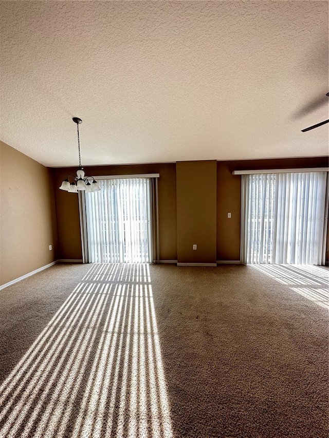 unfurnished living room featuring carpet flooring, a notable chandelier, and a textured ceiling