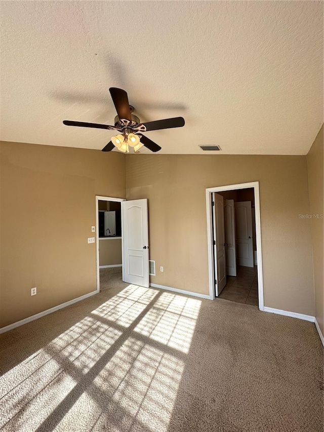 unfurnished bedroom featuring vaulted ceiling, carpet flooring, a textured ceiling, and ceiling fan