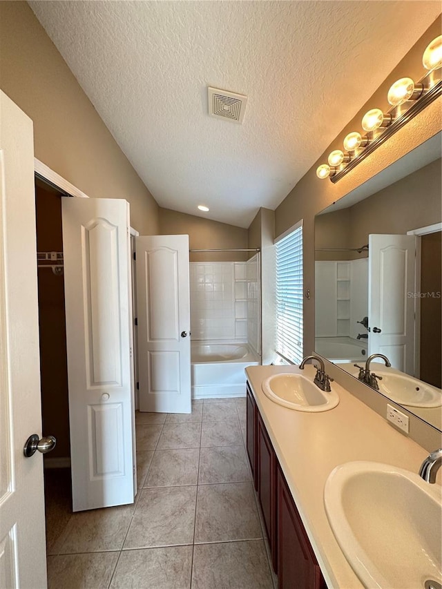 bathroom with lofted ceiling, vanity, tile patterned floors, and shower / washtub combination