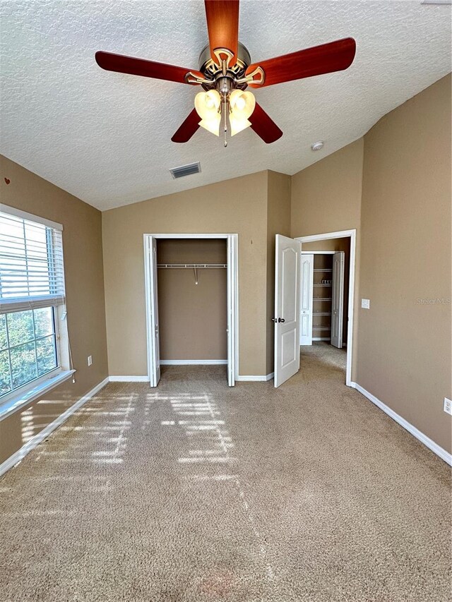 unfurnished bedroom featuring lofted ceiling, ceiling fan, a textured ceiling, light carpet, and a closet