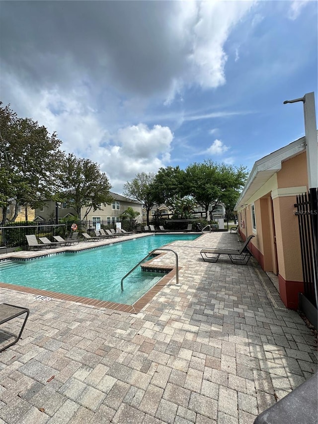 community pool with a patio and fence