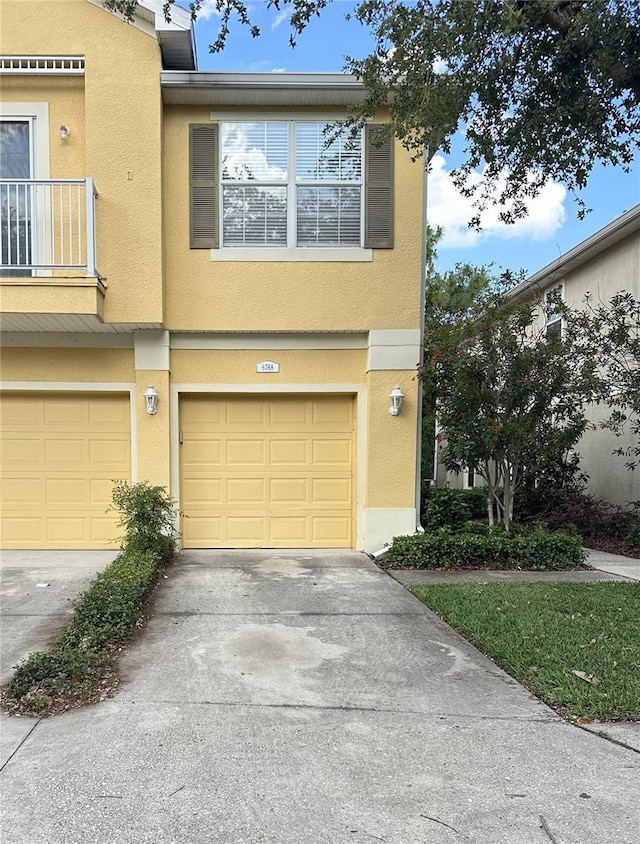 view of property featuring a garage, stucco siding, and driveway