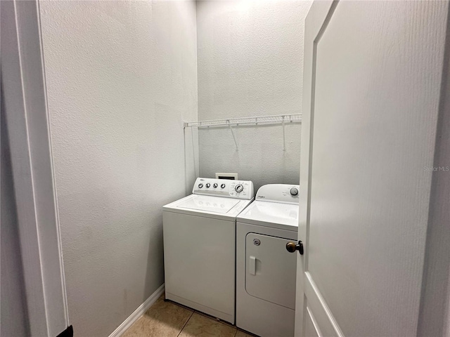 washroom with laundry area, light tile patterned floors, baseboards, and washing machine and clothes dryer