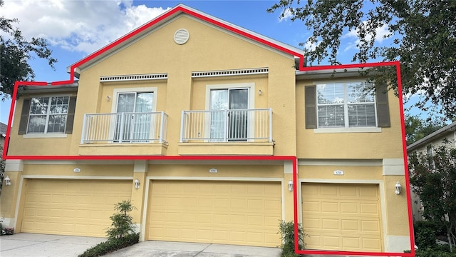 view of property featuring a garage, stucco siding, and a balcony