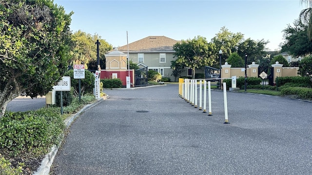 view of road featuring street lighting, a gated entry, curbs, and traffic signs