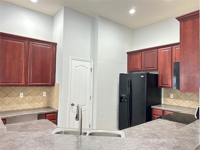kitchen featuring dark brown cabinets, a sink, black appliances, backsplash, and recessed lighting