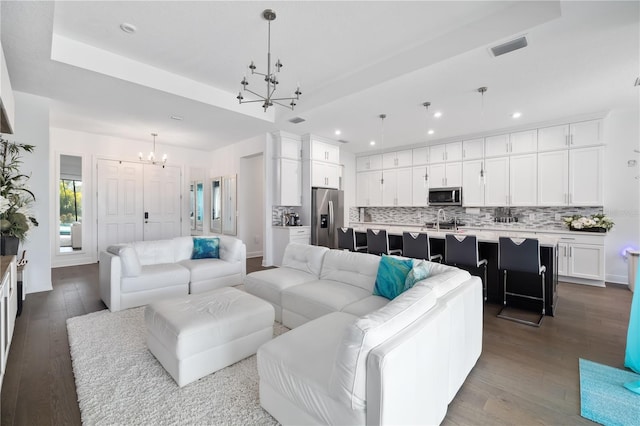 living room with wood-type flooring, a chandelier, and a raised ceiling