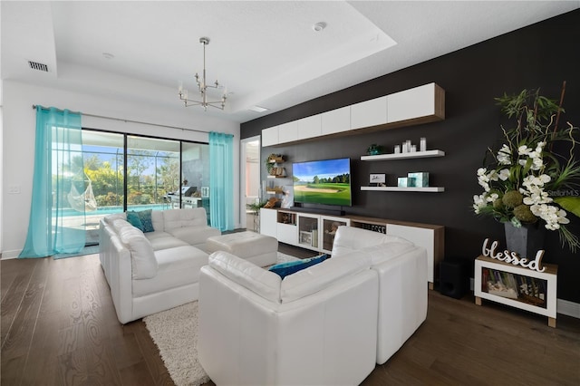 living room with dark wood-type flooring, a chandelier, and a tray ceiling