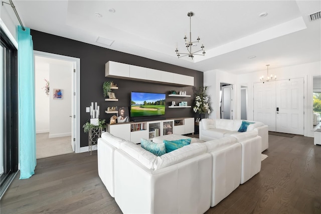 living room featuring a tray ceiling, dark hardwood / wood-style floors, and a chandelier