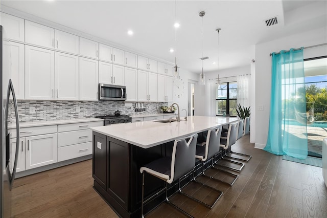 kitchen with decorative light fixtures, sink, a kitchen breakfast bar, a kitchen island with sink, and stainless steel appliances