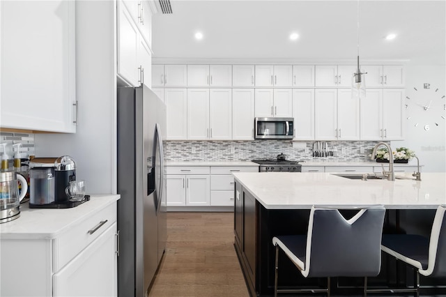 kitchen with sink, white cabinets, hanging light fixtures, light stone counters, and stainless steel appliances