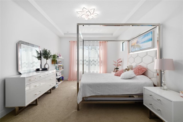 bedroom with light colored carpet and a tray ceiling