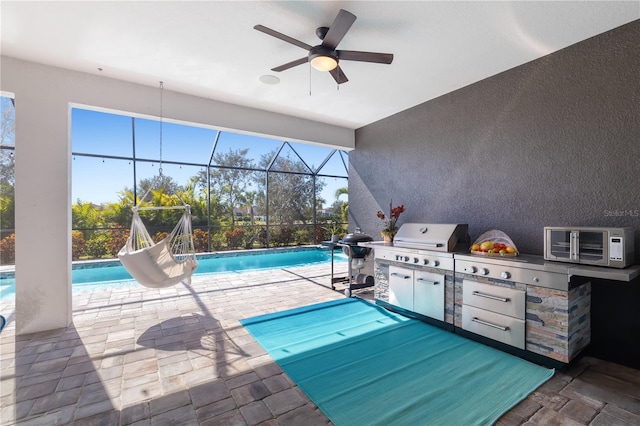 view of pool with a grill, a patio area, ceiling fan, and exterior kitchen