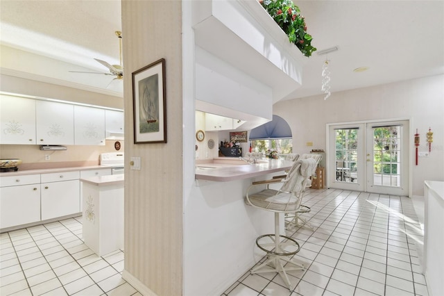 kitchen featuring electric range, french doors, white cabinetry, a kitchen breakfast bar, and light tile patterned floors