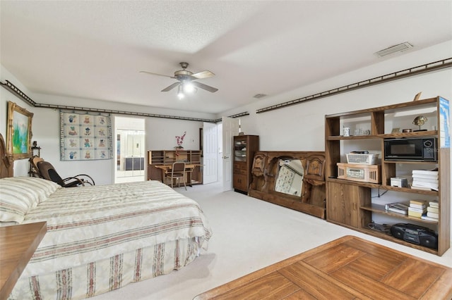 bedroom with light colored carpet, a textured ceiling, ceiling fan, and ensuite bath