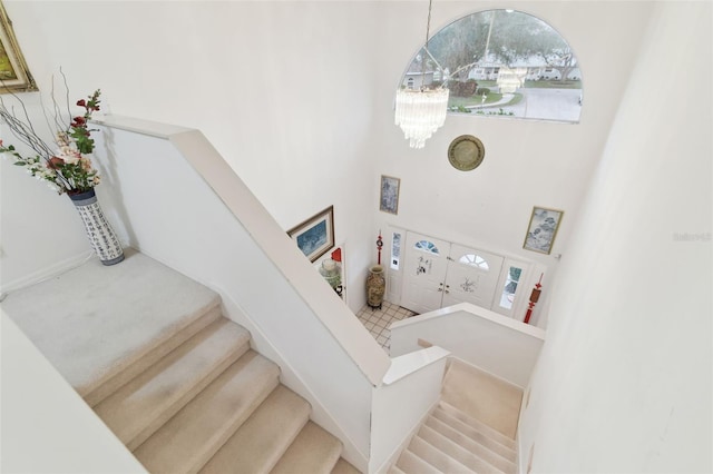 stairs featuring an inviting chandelier and a towering ceiling