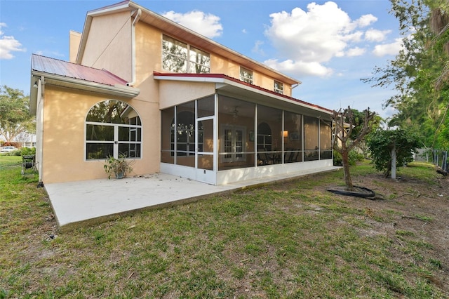 back of property with a patio area, a sunroom, and a lawn