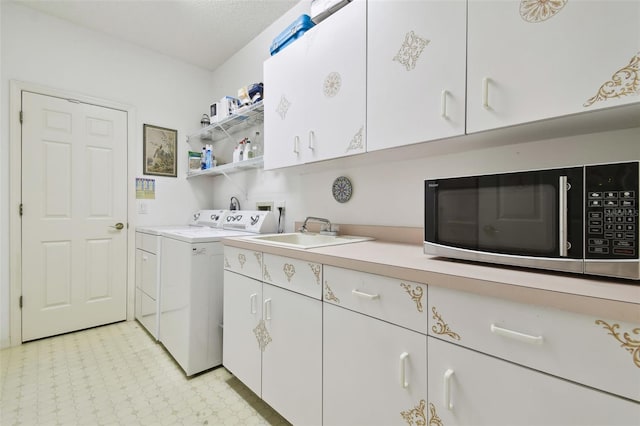 laundry room with washing machine and clothes dryer, cabinets, and sink