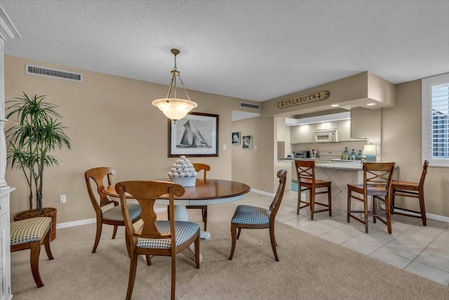 dining space with light colored carpet and a textured ceiling