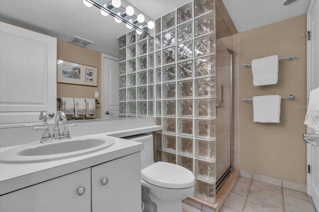 bathroom featuring tile patterned flooring, vanity, toilet, and walk in shower