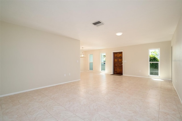 empty room featuring light tile patterned floors and an inviting chandelier