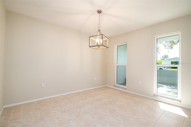 tiled empty room featuring an inviting chandelier